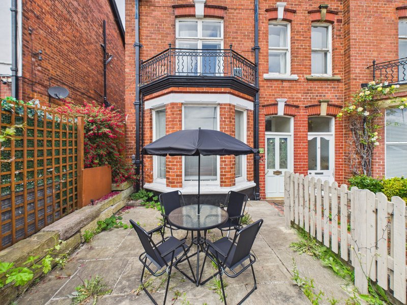 Brick townhouse exterior with patio seating area, garden furniture and umbrella