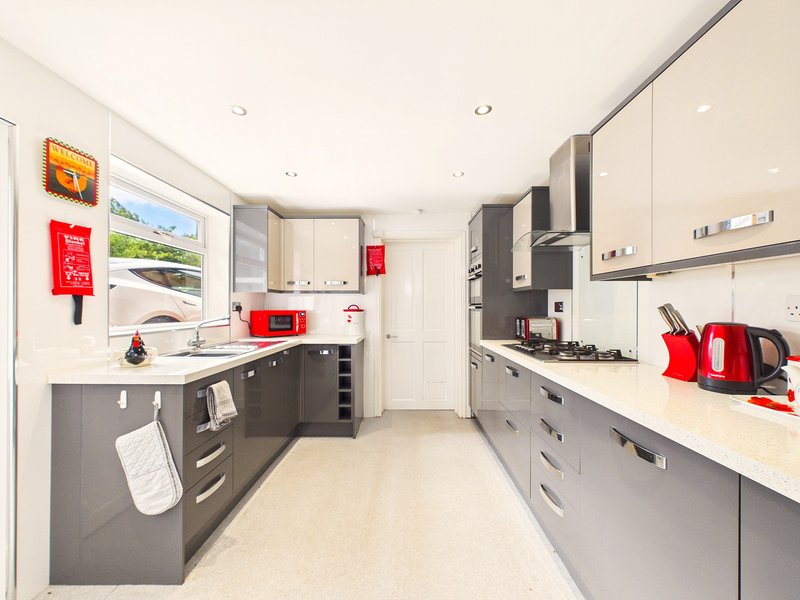 Modern kitchen with grey and white cabinetry, red appliances, and breakfast bar seating