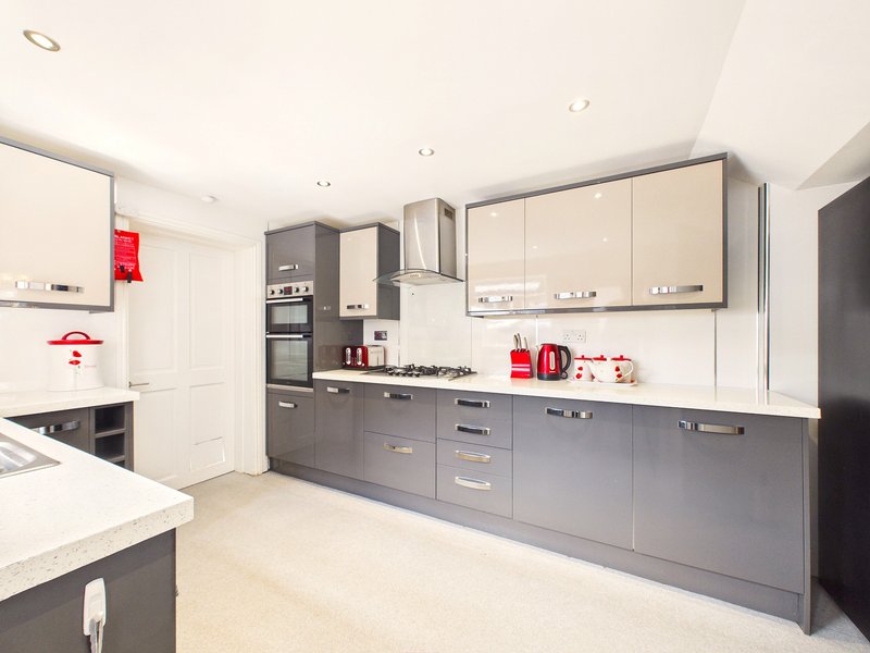 Modern kitchen with grey and white cabinetry, stainless steel appliances, white countertops and island