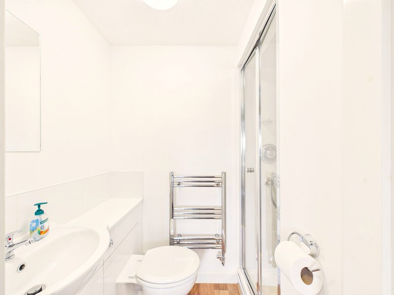 Small modern bathroom with white suite, chrome towel rail and shower enclosure