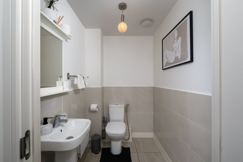 Small bathroom with sink, toilet, mirror, pendant light and framed wall art