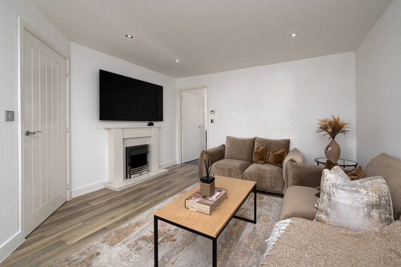 Modern living room with fireplace, wall-mounted TV, beige armchair and coffee table