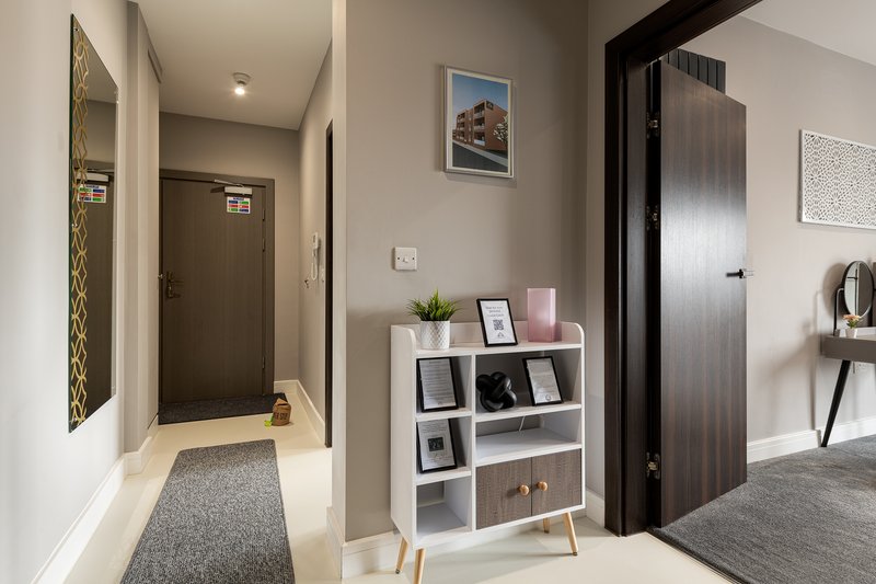 Modern hallway with white walls, storage shelving unit, framed artwork, and dark doors