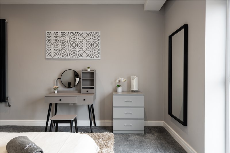 Modern bedroom with vanity desk, mirror, chest of drawers and wall art