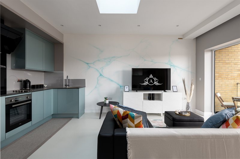 Open-plan living room with modern kitchen, marble accent wall, and contemporary furniture