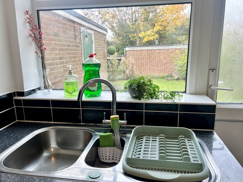 Kitchen sink with window overlooking brick garden building and green lawn