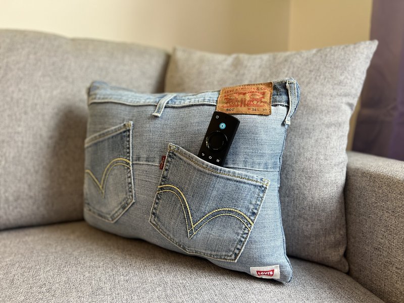 Beige sofa with decorative cushion made from denim jeans material and small objects