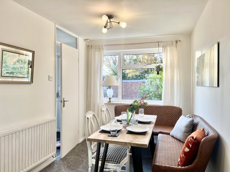 Bright dining area with wooden table, brown leather seating, window with garden view