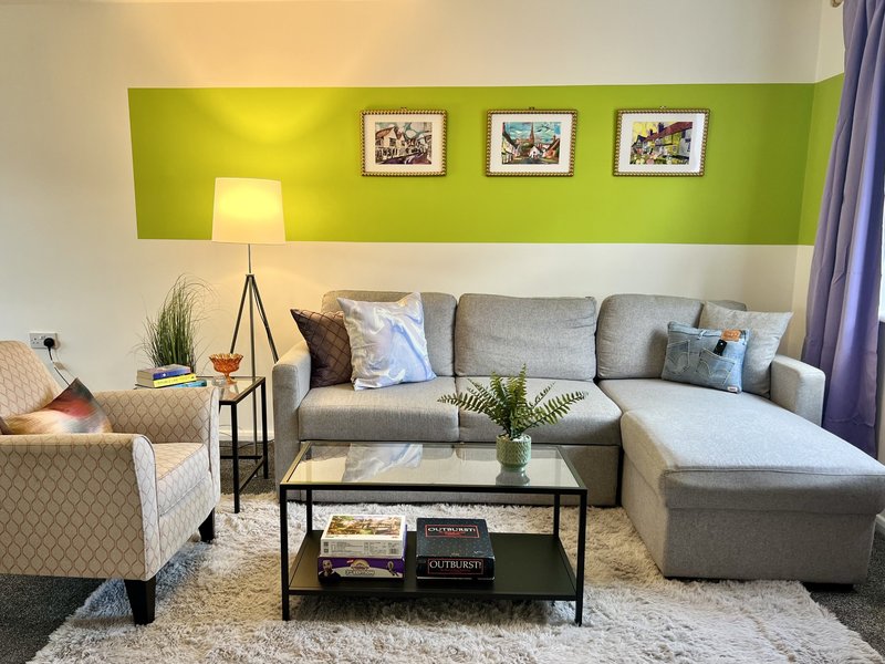 Modern living room with gray sectional sofa, armchair, coffee table, and green accent wall