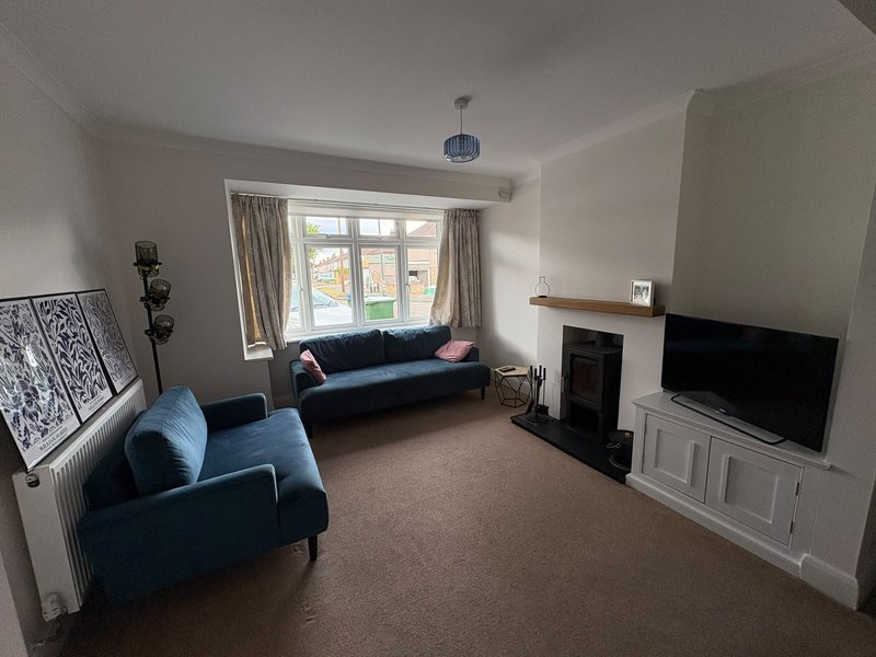 Living room with blue sofa and armchair, fireplace, TV, and large window with curtains