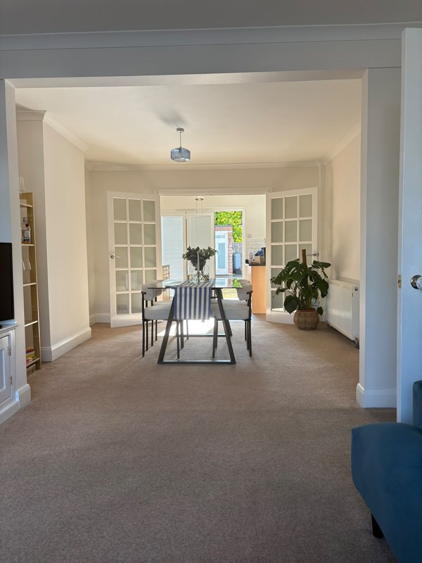 Open-plan dining area with table, chairs, potted plant and glass doors to garden