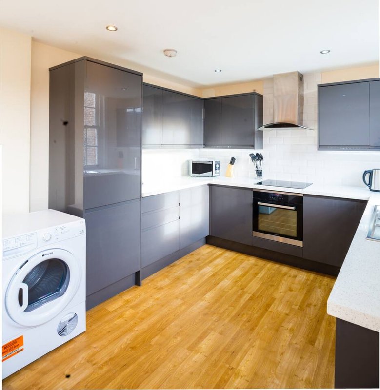 Modern kitchen with dark cabinetry, white countertops, wooden flooring, and integrated appliances