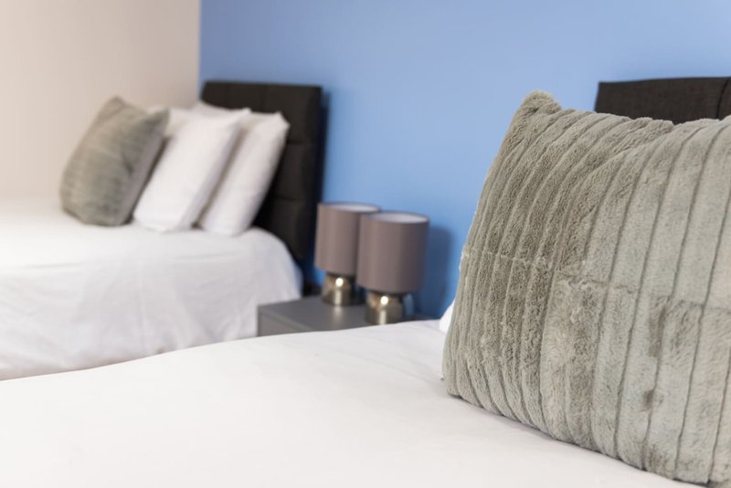 Bedroom with two beds, black headboards, white bedding, and gray decorative pillows