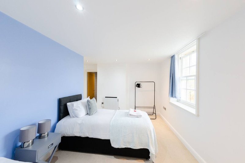Modern bedroom with double bed, blue accent wall, white bedding and large window