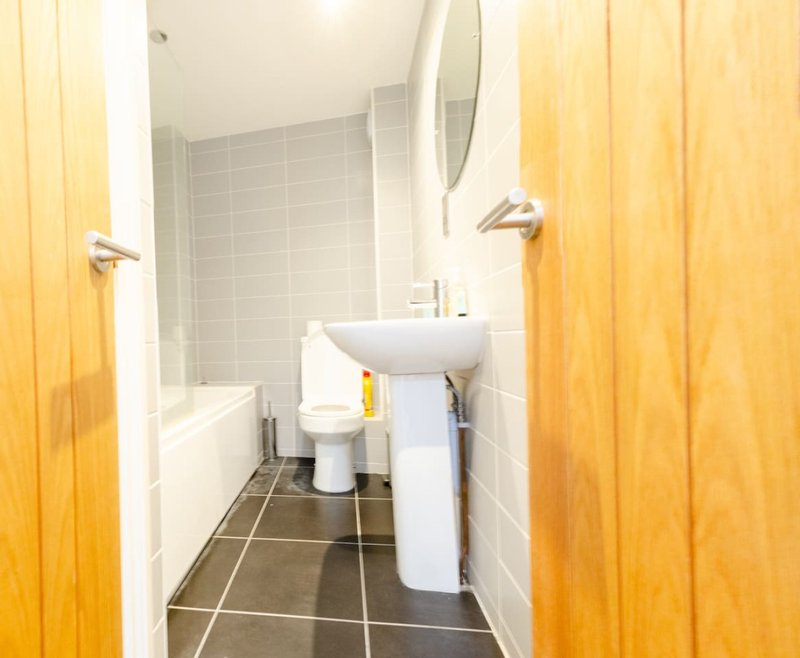 Small bathroom with toilet, pedestal sink, tiled walls and dark floor