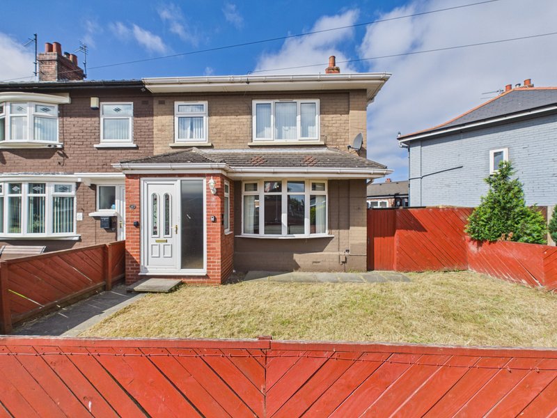 Semi-detached brick house with driveway, front garden and red fencing
