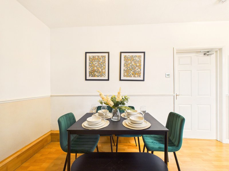 Dining room with black table, green chairs, place settings and yellow flowers