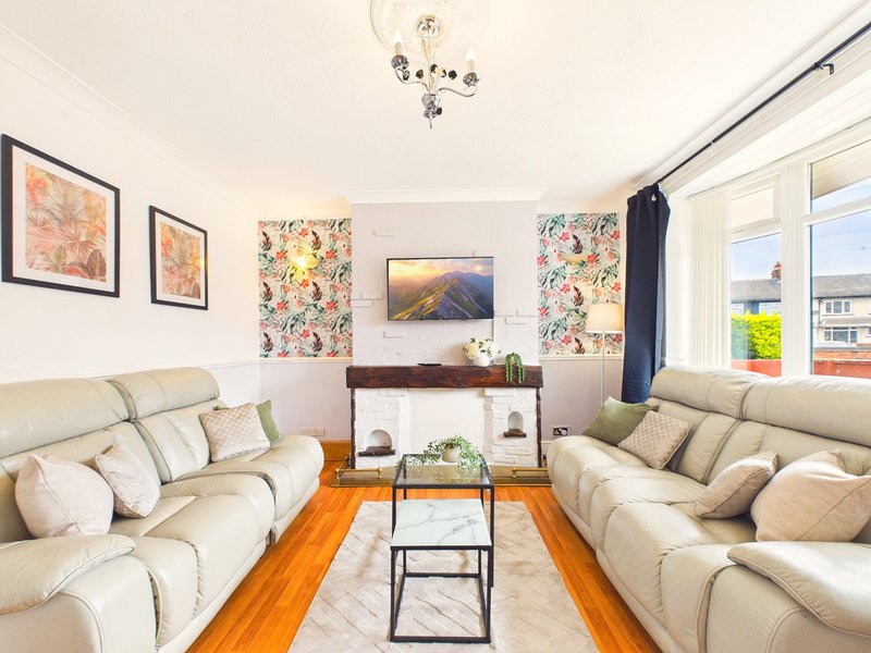 Modern living room with two cream leather sofas, wooden floor, framed artwork and mountain landscape painting