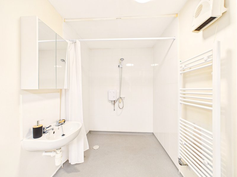 Clean modern bathroom with white sink, mirror cabinet, shower enclosure and heated towel rail