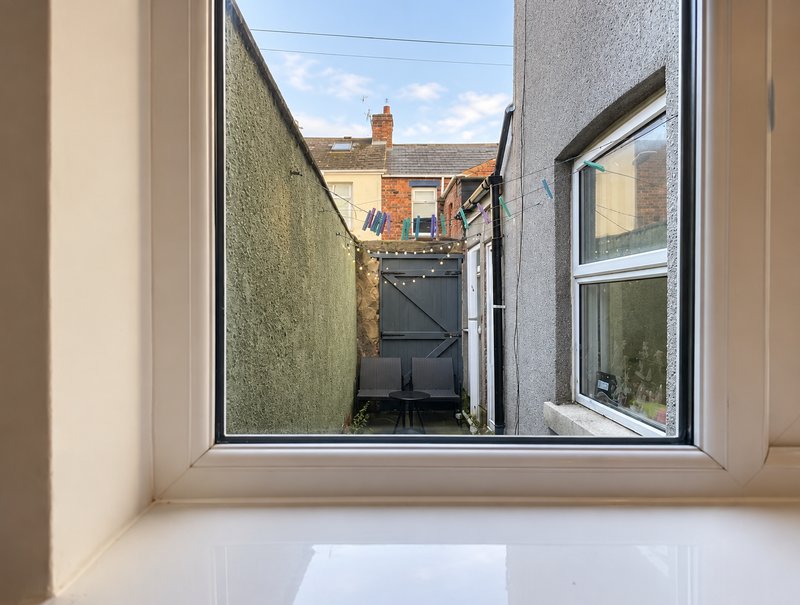 Window view of narrow alleyway between brick buildings with utility gate