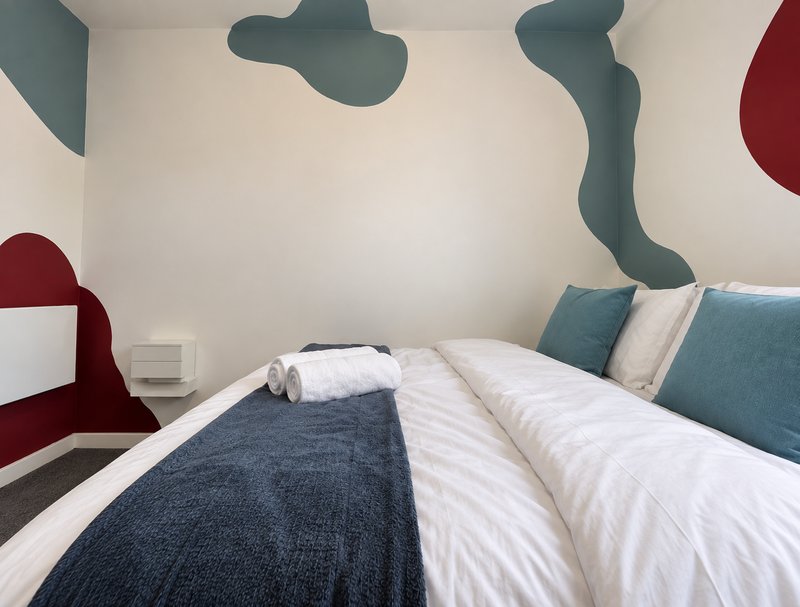 Modern bedroom with twin beds, white bedding, blue cushions and abstract wall art