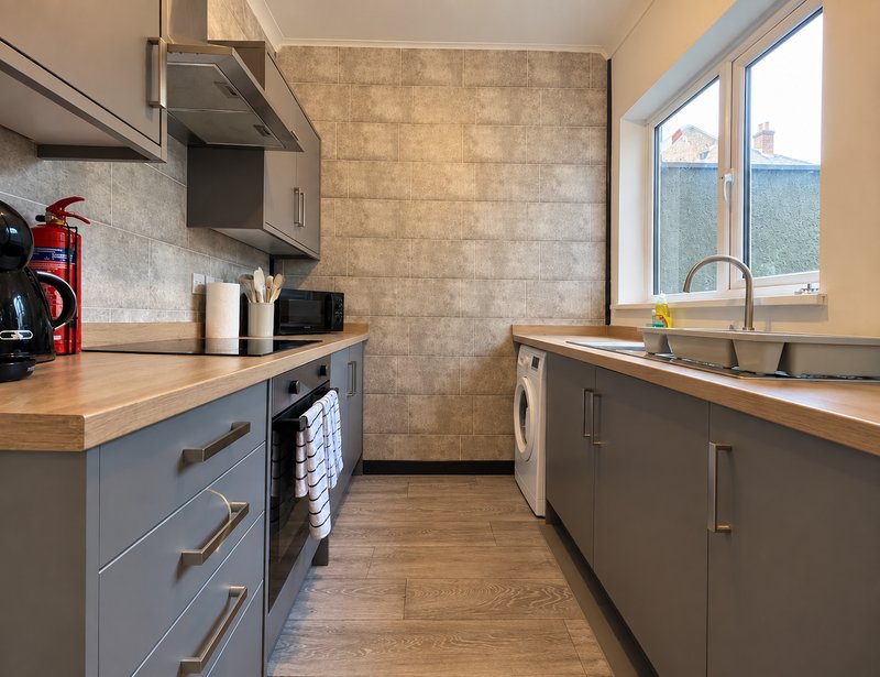 Modern kitchen with gray cabinetry, wooden countertops, stainless steel appliances and window view