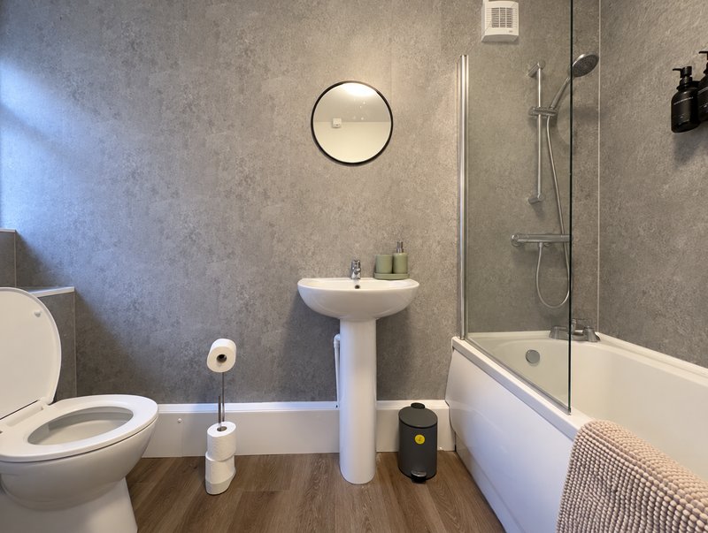 Modern bathroom with toilet, pedestal sink, mirror, shower enclosure and bath
