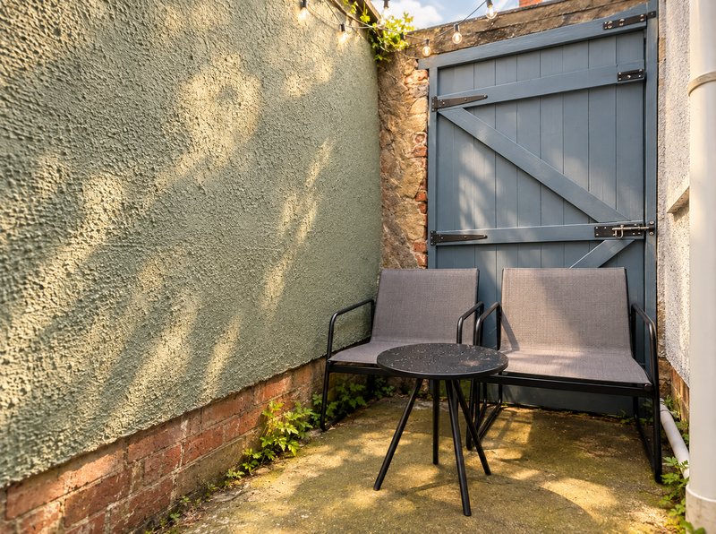 Compact courtyard with grey seating, round table, and brick walls