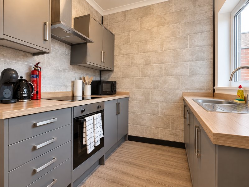 Modern kitchen with gray cabinetry, wooden countertops, built-in oven and stainless steel sink
