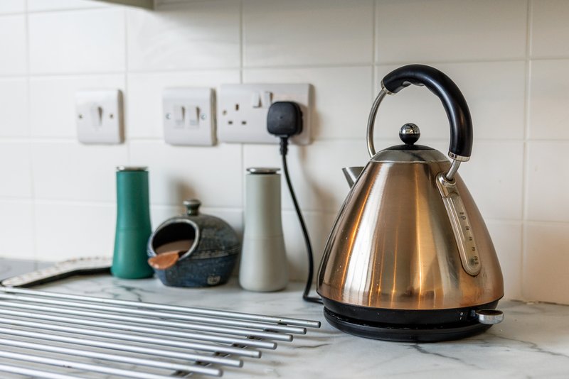 Kitchen countertop with kettle, utensils, soap dispenser, and electrical outlets