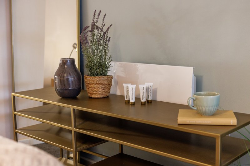 Modern wooden console table with decorative vase, potted plant, toiletries and accessories