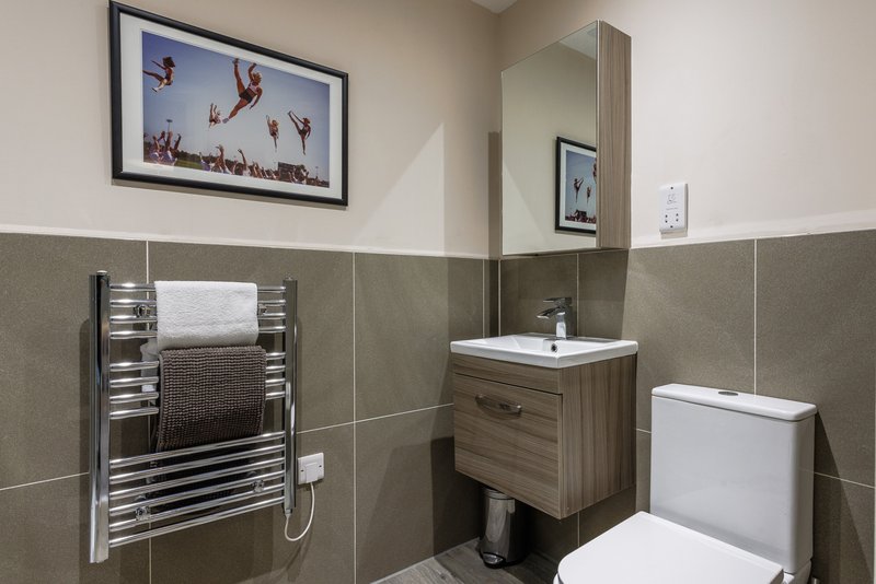 Modern bathroom with heated towel rail, wooden vanity, toilet, and framed wall art