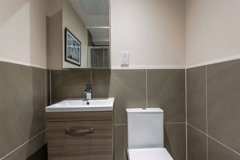 Modern bathroom with vanity sink, toilet, and grey tiled walls