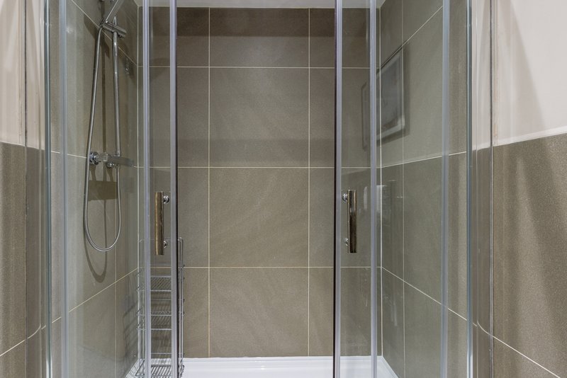 Modern bathroom with enclosed glass shower cubicle and tiled walls