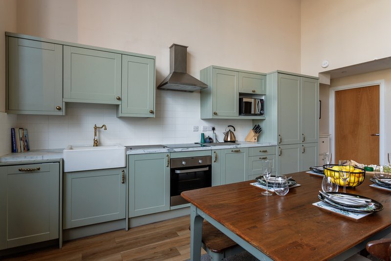 Modern kitchen with sage green cabinets, wooden island countertop, and stainless steel appliances