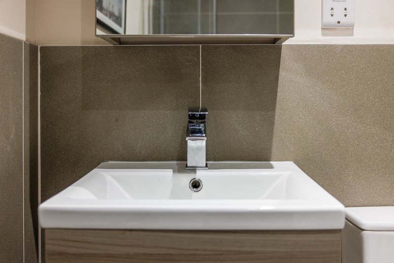 Modern bathroom sink with chrome tap, white basin and beige tiled walls