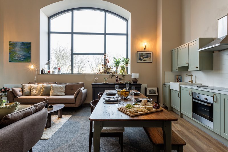Open-plan living space with kitchen, dining table, and seating area with arched window