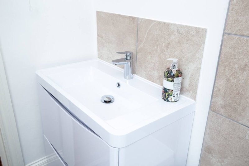 Modern bathroom sink with white vanity, chrome faucet and tiled backsplash