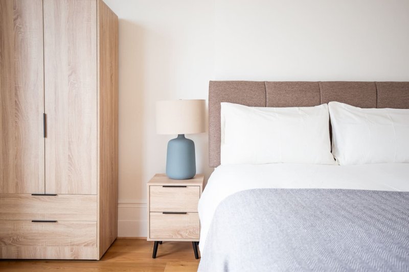Modern bedroom with double bed, gray headboard, wooden wardrobe and bedside table