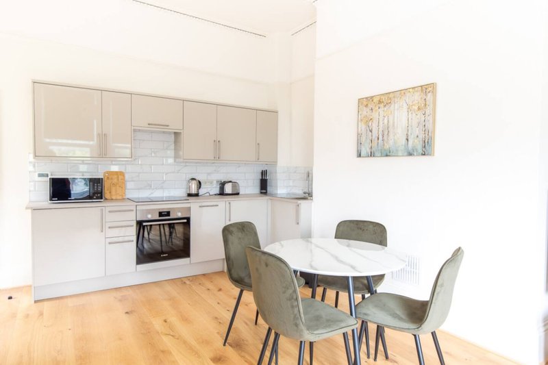 Open-plan kitchen and dining area with cream cabinetry, dining table, and wooden flooring