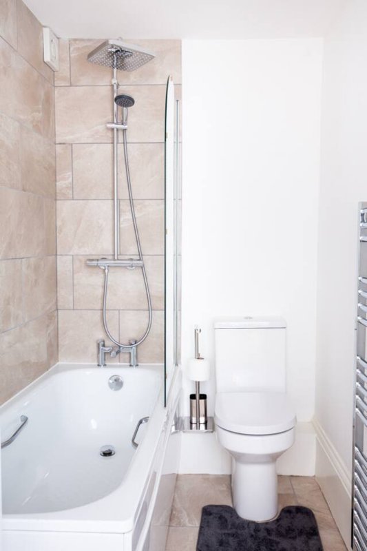 Compact bathroom with bath, shower, toilet and heated towel rail