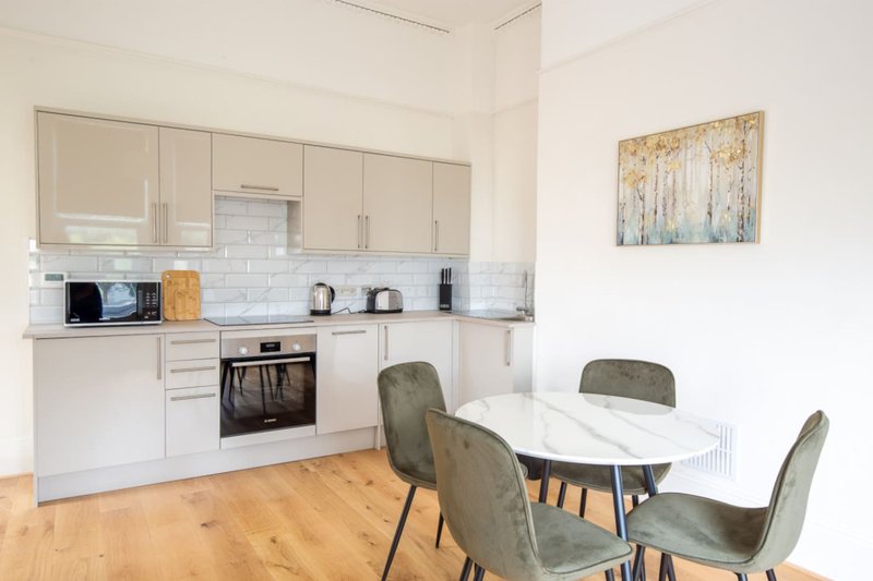 Open-plan kitchen and dining area with cream cabinetry, dining table and grey chairs