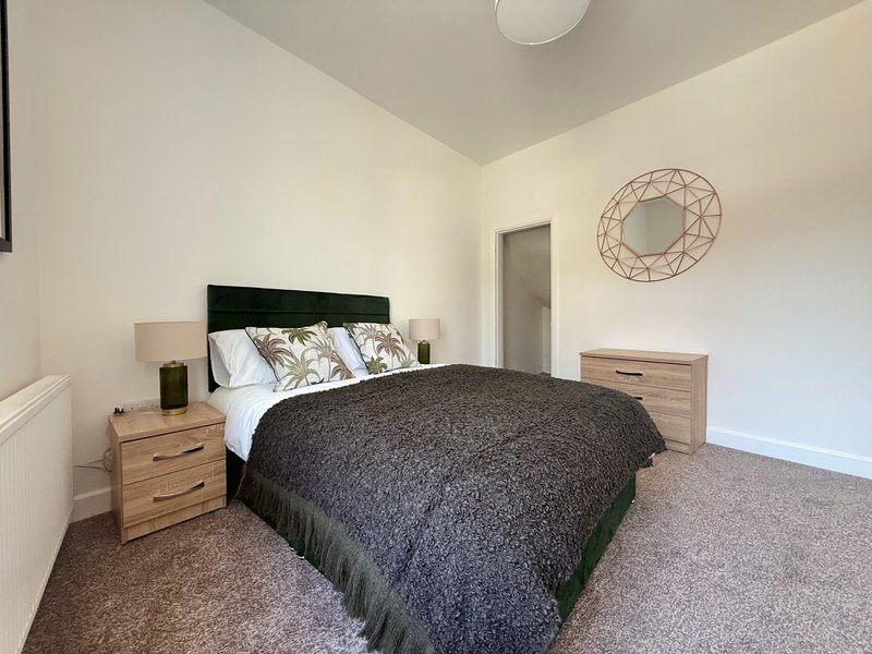 Bright bedroom with double bed, wooden nightstands, black headboard and wall decor