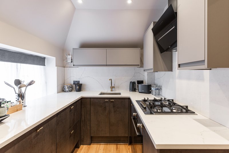 Modern kitchen with dark wood cabinets, white countertops, gas hob and built-in appliances