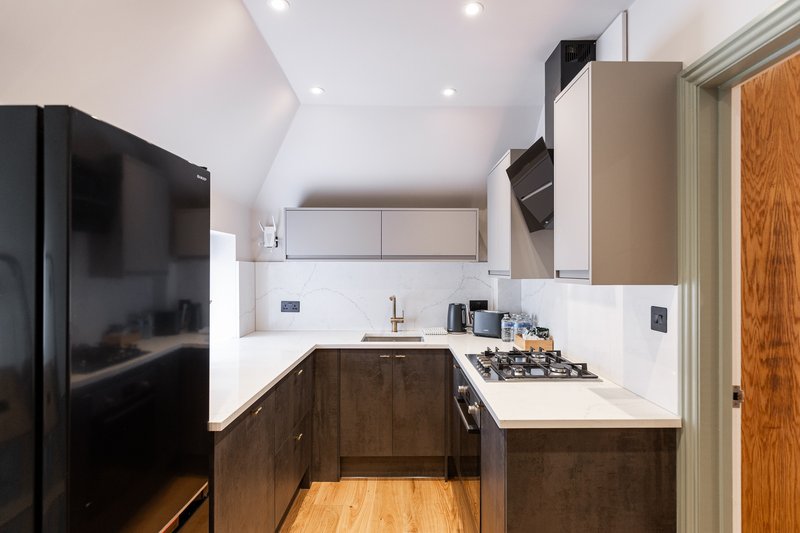 Modern kitchen with dark wood cabinets, white countertops, gas cooktop, and stainless steel appliances