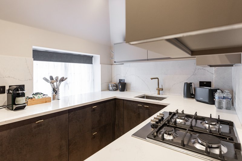 Modern kitchen with dark cabinetry, white countertop, gas cooktop and stainless steel sink