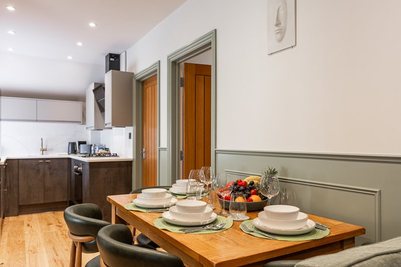 Dining table set for four with wooden top, kitchen and wooden doors visible behind