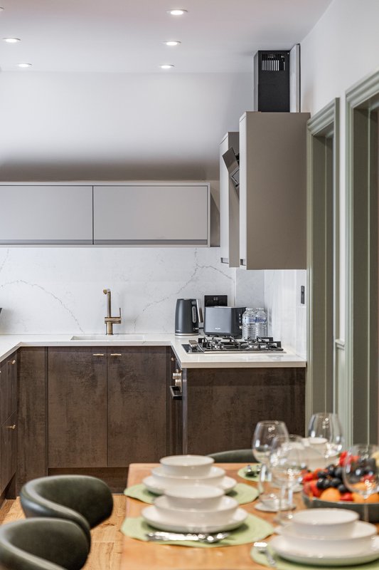 Modern kitchen with dark wood cabinetry, white marble backsplash, and dining table set with place settings