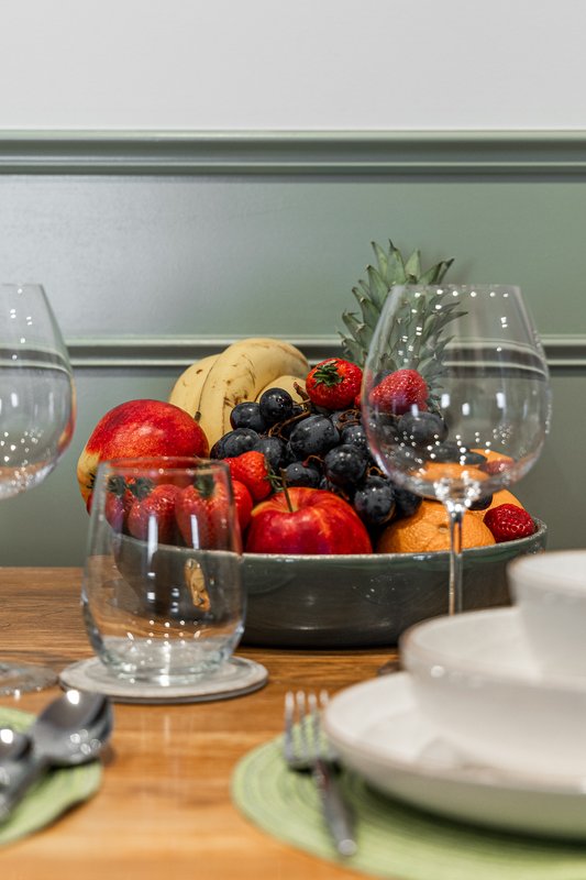 Dining table with fruit bowl, glasses, plates and place settings