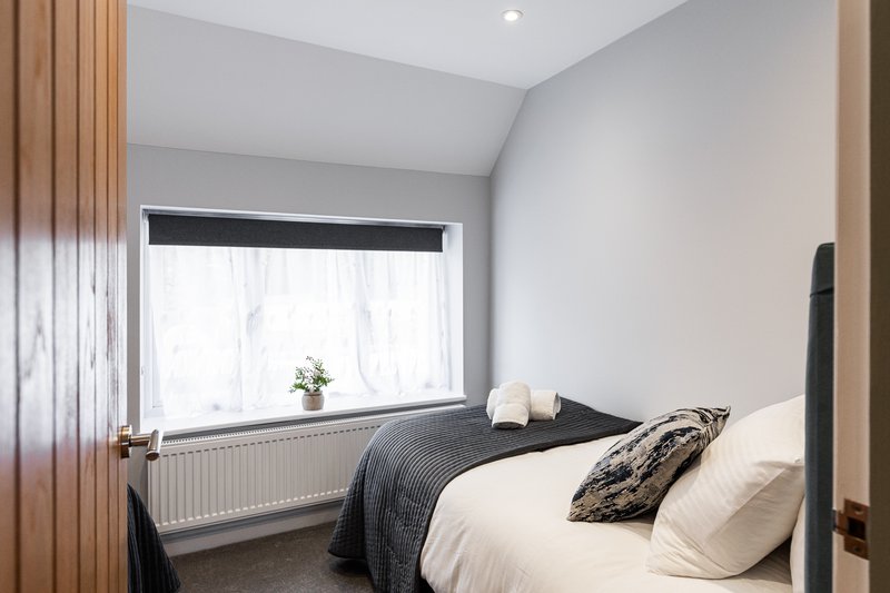 Bedroom with double bed, window, radiator, and wooden wardrobe doors